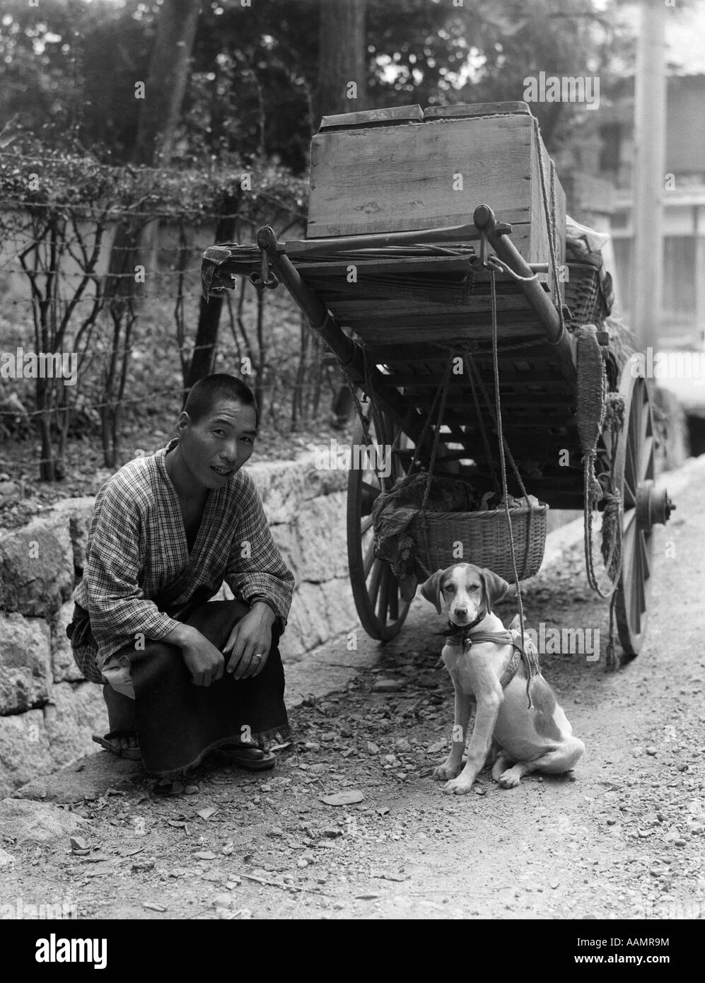 1930 HOMME JAPONAIS VENDEUR DE LÉGUMES PANIER fermier avec le bas-côté de la route s'agenouillant SMILING WITH PAR CHIEN JAPON Banque D'Images