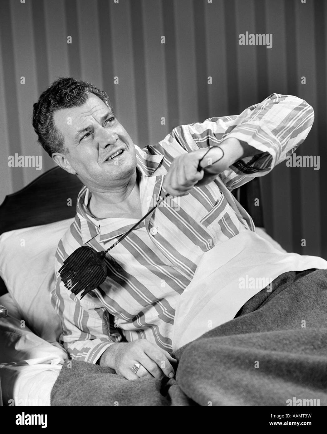 1940 MAN SITTING IN BED WITH FLYSWATTER Banque D'Images