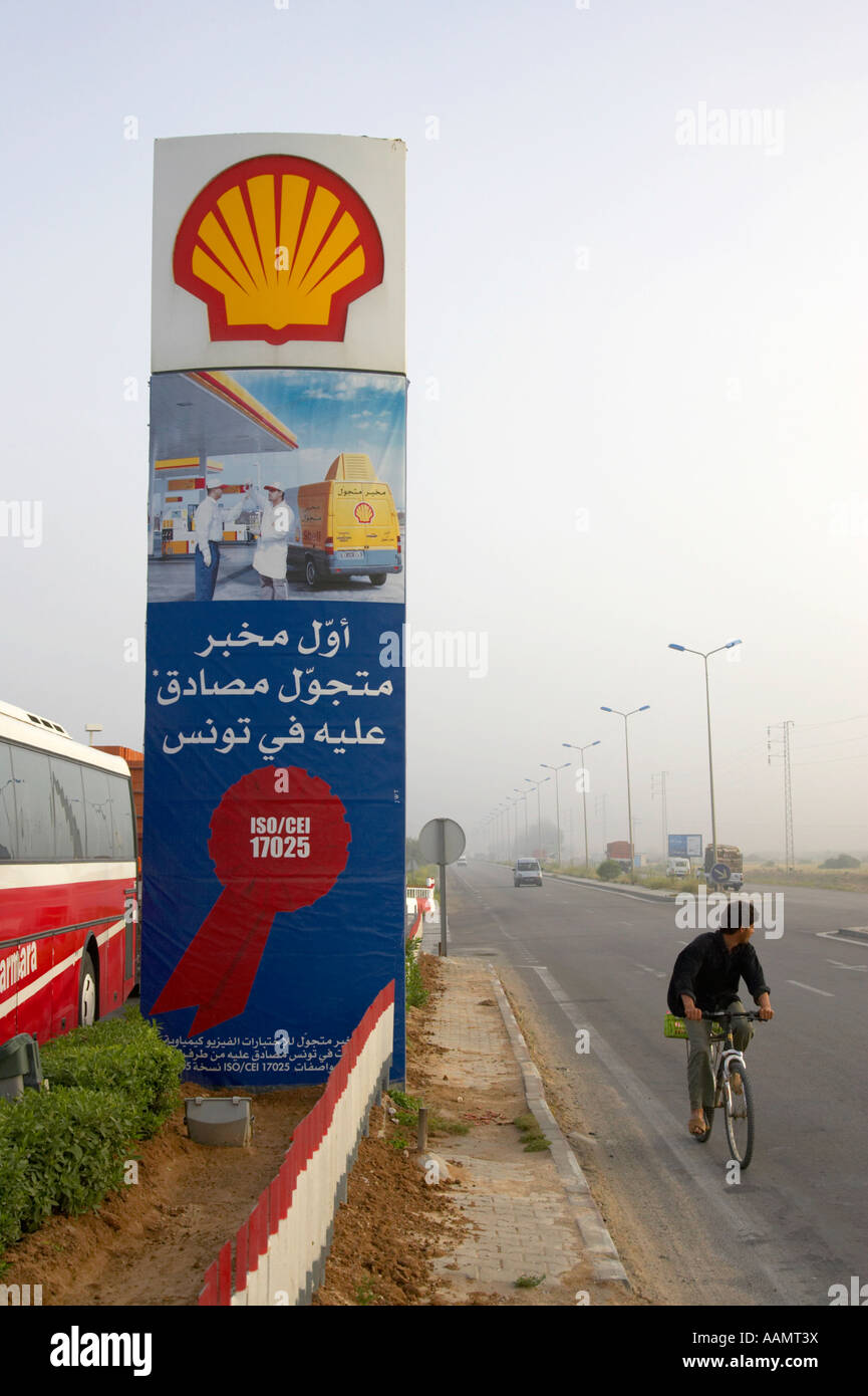 Vélo homme passé garage shell signe sur l'autoroute à l'extérieur vertical Sousse Tunisie Banque D'Images