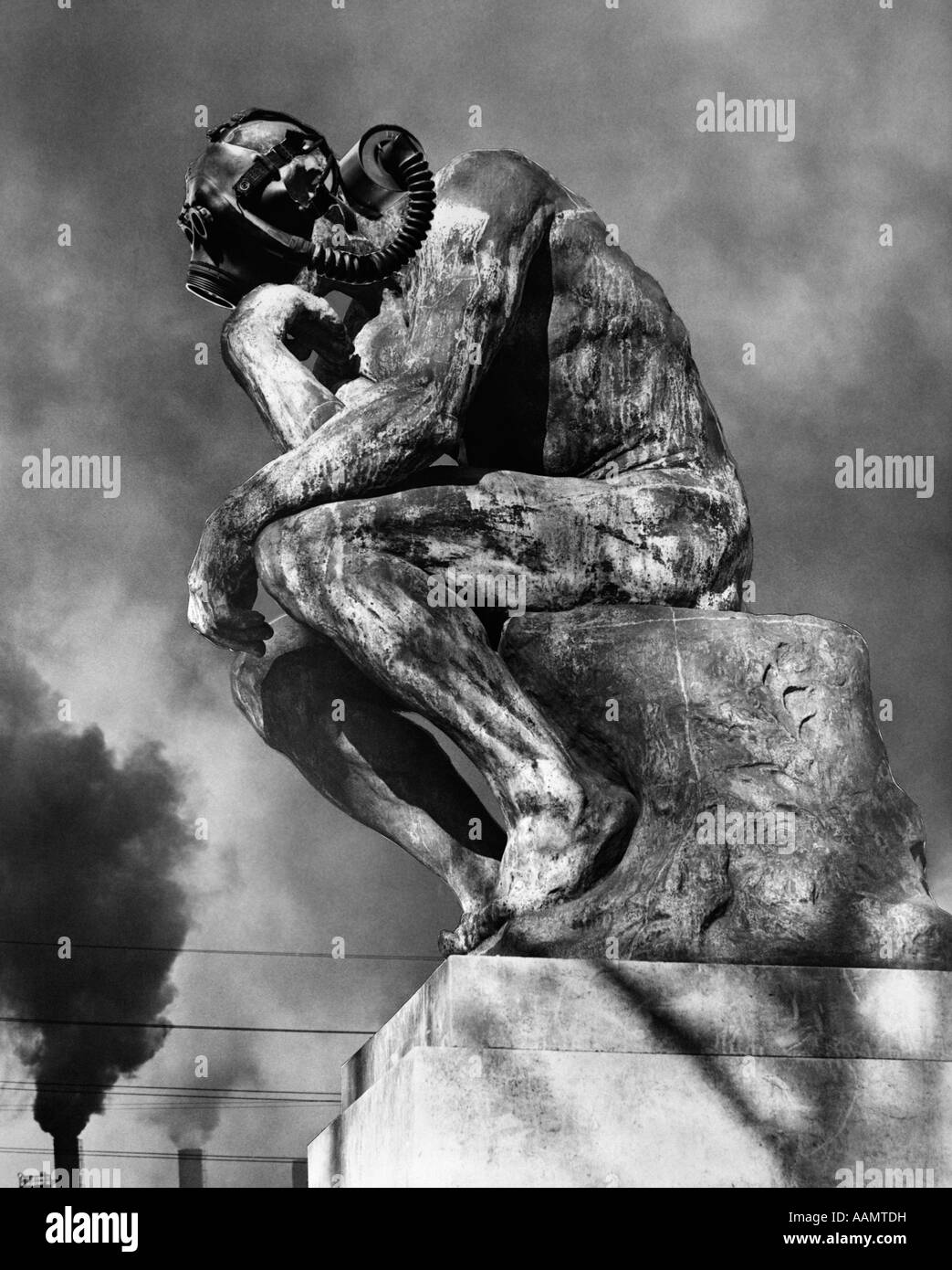 1970 STATUE DE PENSEUR DE RODIN PORTANT UN MASQUE À GAZ AVEC CHEMINÉES d'échapper en arrière-plan Banque D'Images