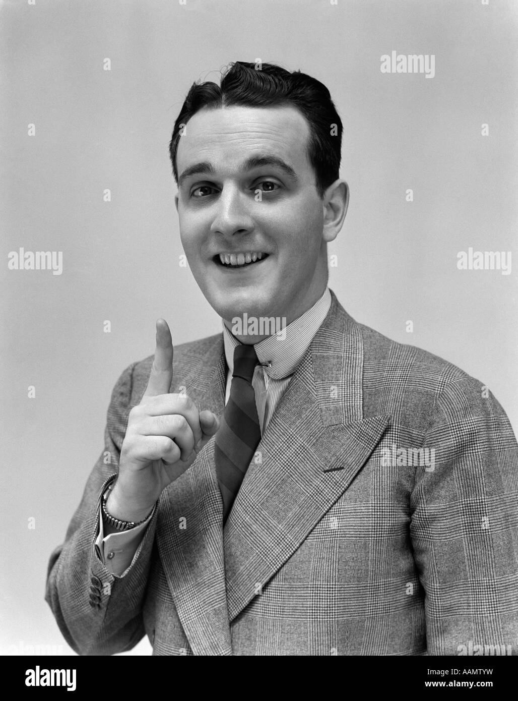 1940 MAN IN SUIT HOLDING UP INDEX FAIRE UN POINT Banque D'Images