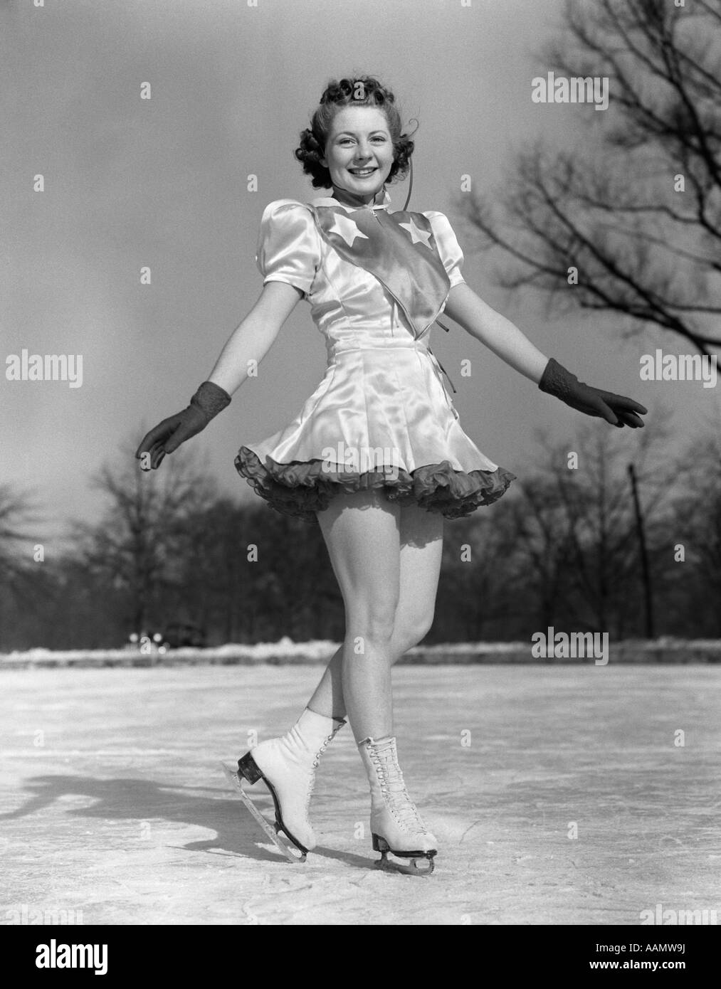 1940 SMILING WOMAN, patineuse artistique PERFORMER SUR LA GLACE PORTANT DES GANTS ET LOOKING AT CAMERA Banque D'Images