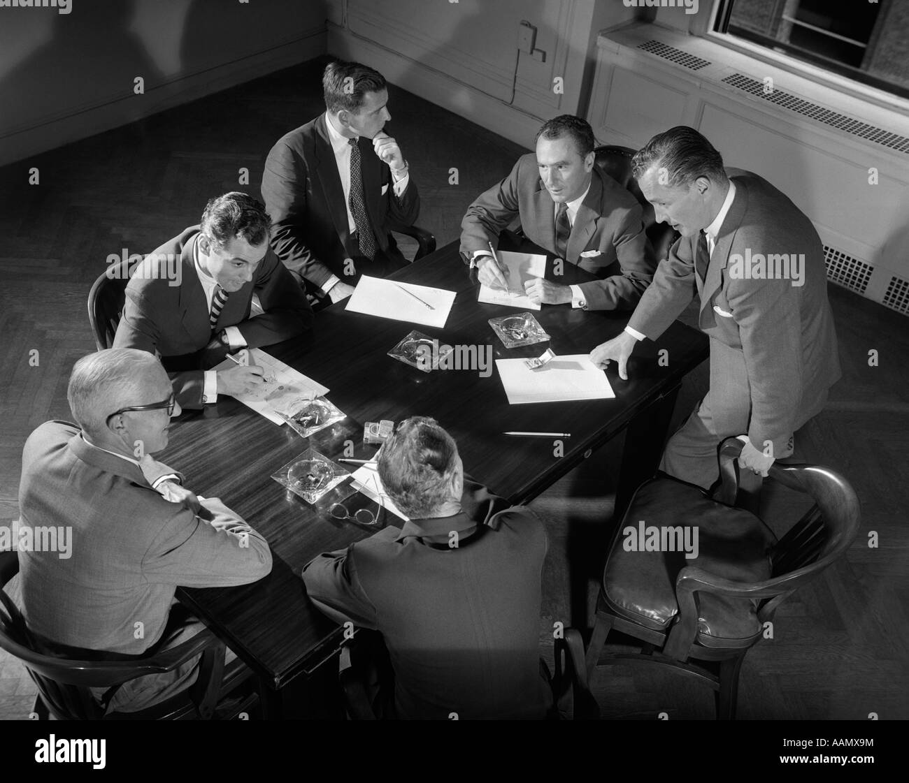 Années 1950, six hommes en costumes d'affaires commerciaux AUTOUR DE LA RÉUNION DE LA TABLE DE CONFÉRENCE Banque D'Images