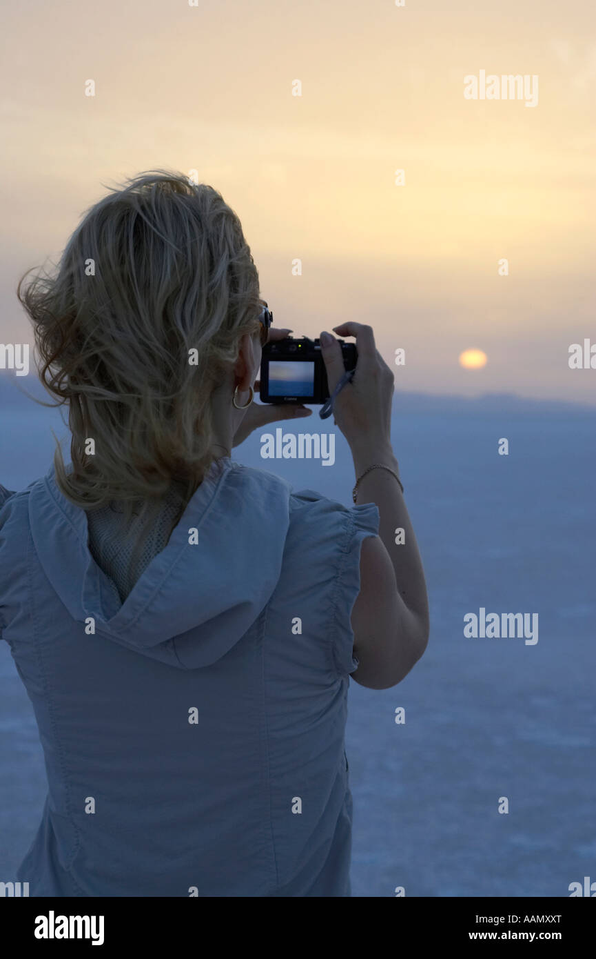 Femme aux cheveux blonds vertical'prend une photographie du soleil se levant sur le lac salé chott El Djerid tunisie Banque D'Images