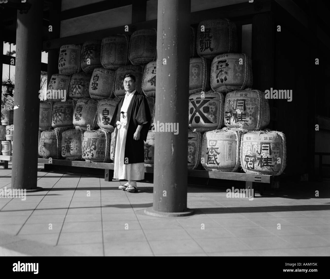 Années 1920 Années 1930 HOMME JAPONAIS DANS DES ROBES souverain sacrificateur, debout au milieu des fûts de vin de riz saké sacré Sanctuaire Heian AU JAPON Banque D'Images