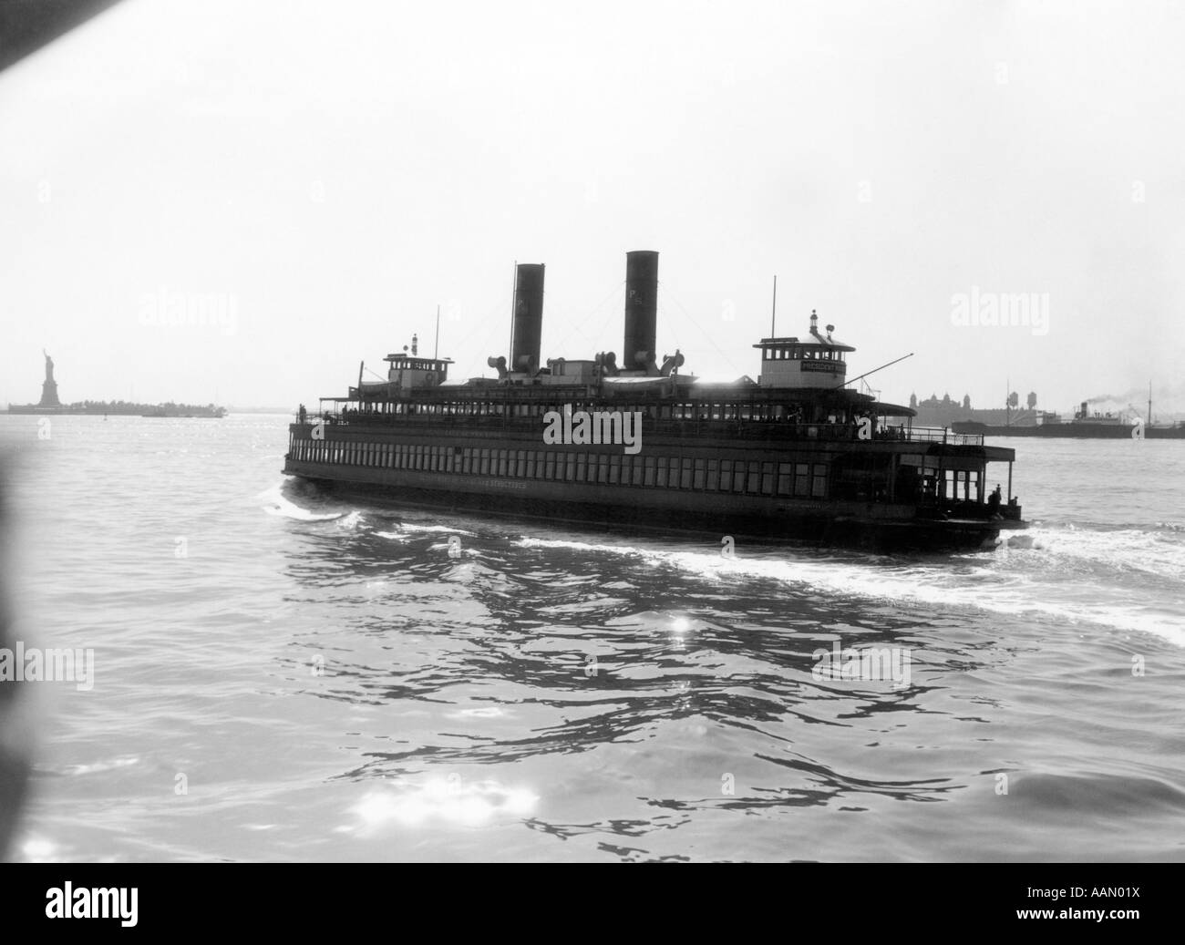 Années 1930, NEW YORK CITY HARBOR FERRY BATEAU AVEC DEUX CHEMINÉES VUE DEPUIS L'ARRIÈRE DE LA STATUE DE LA LIBERTÉ À L'HORIZON Banque D'Images