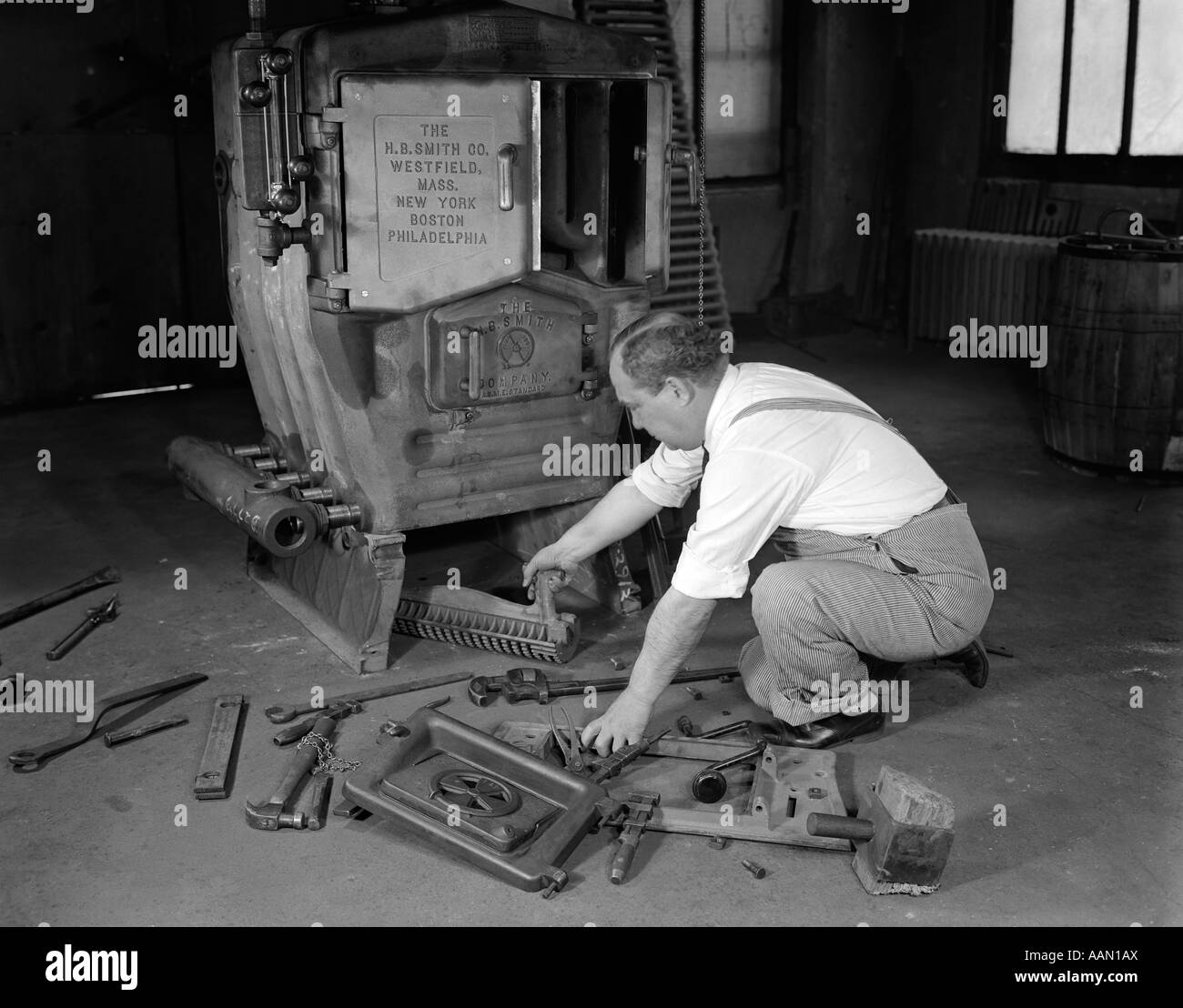 1930 MAN PLOMBIER CONVERTIR LE CHARBON four brûlant pour chaudières de chauffage au gaz Banque D'Images