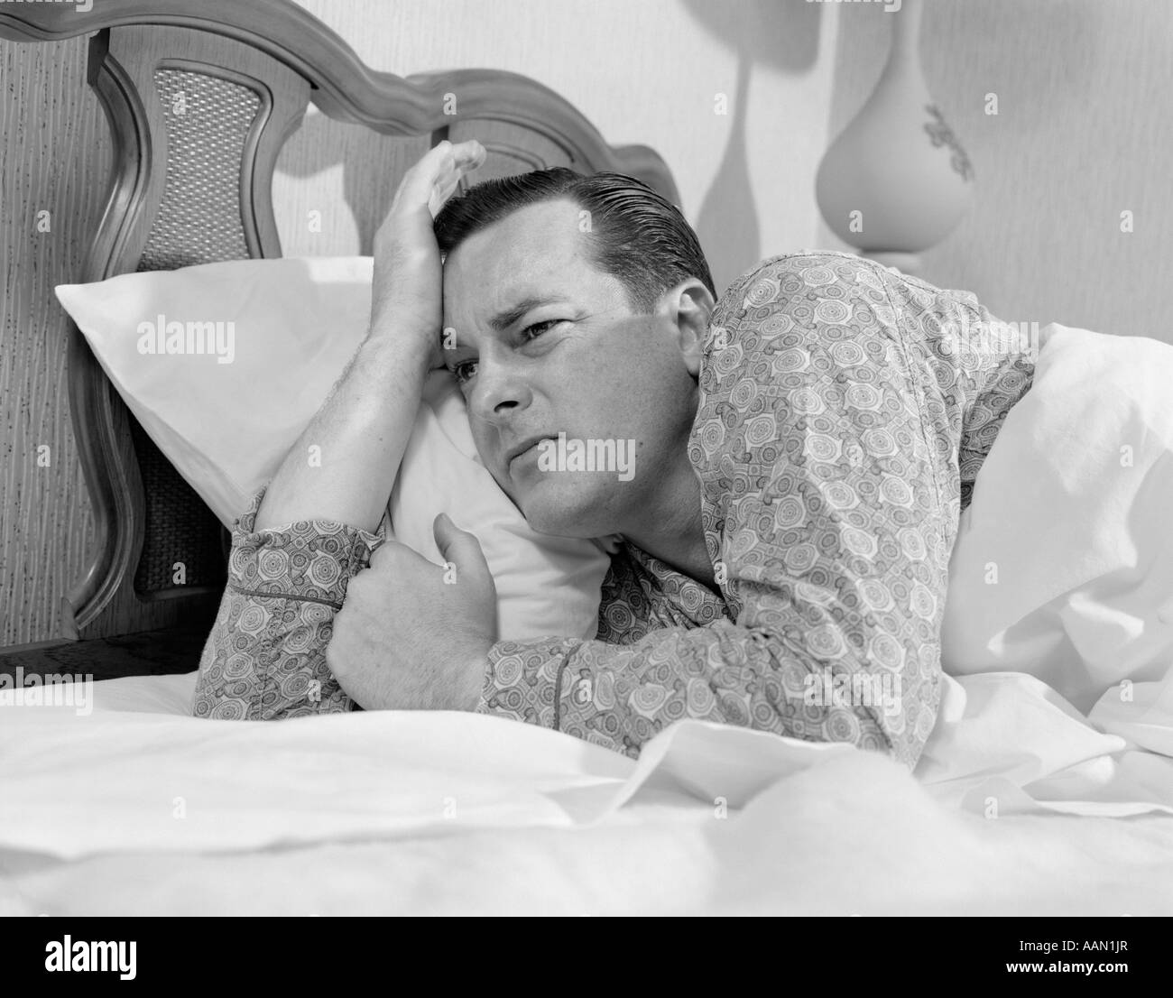1960 L'HOMME DANS LE LIT ALLONGÉ SUR LE CÔTÉ ÉVEILLÉ INCAPABLE DE DORMIR A INSISTÉ SUR L'expression du visage de l'Insomnie PYJAMAS RETRO VINTAGE Banque D'Images
