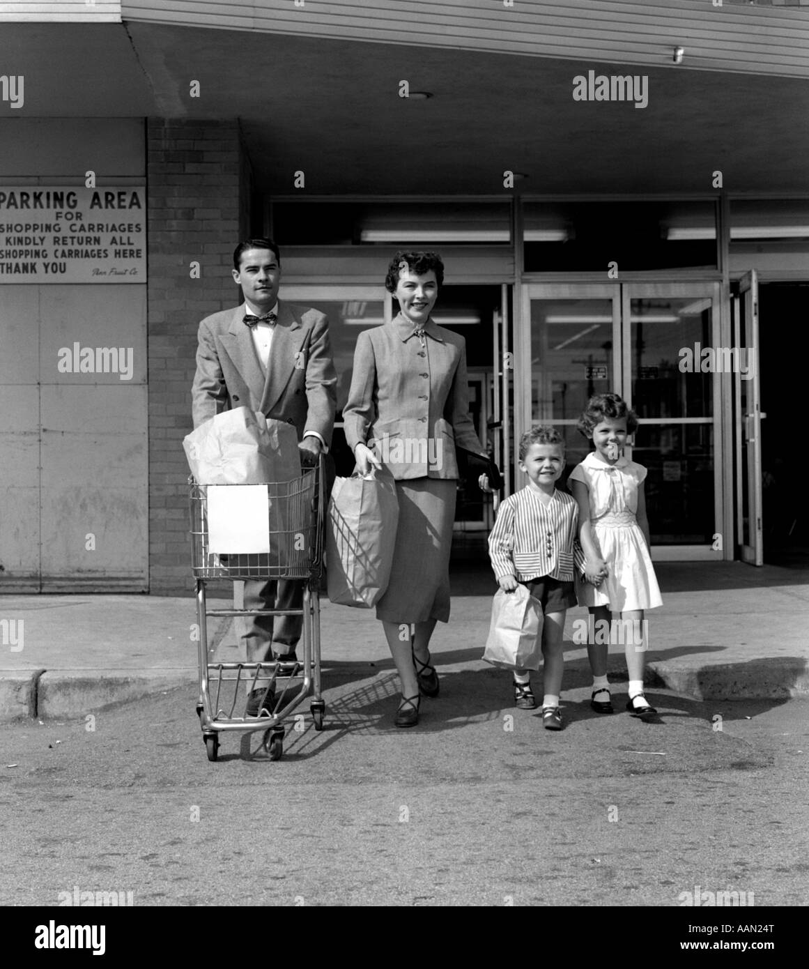 1950 FAMILLE HOMME FEMME Fille Garçon SORTANT DE SUPERMARCHÉ STORE SACS DE TRANSPORT, Mère et Fils Père poussant chariot d'épicerie Banque D'Images
