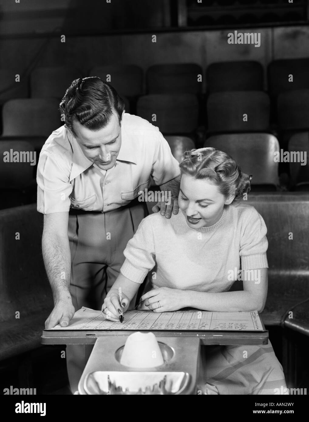 1950 BOWLING COUPLE HOMME À BORD AU-DESSUS DE L'ÉPAULE DE LA FEMME Banque D'Images