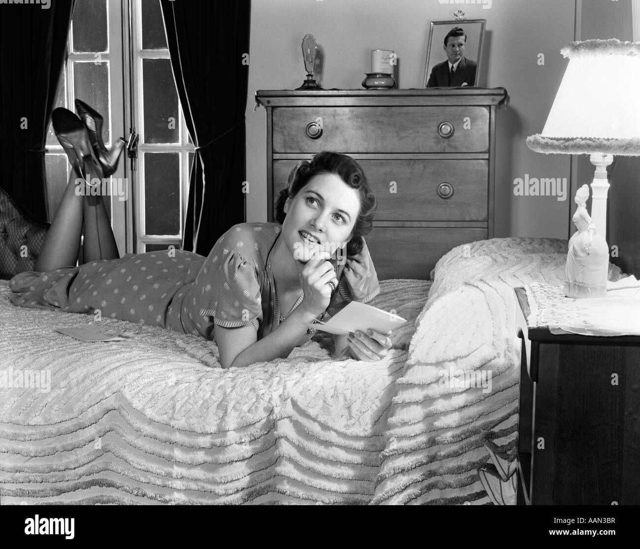 1940 EN TENUE FEMME PORTANT SUR SON DOS avec ses jambes jusqu'à lire une  lettre dans sa chambre à coucher Photo Stock - Alamy