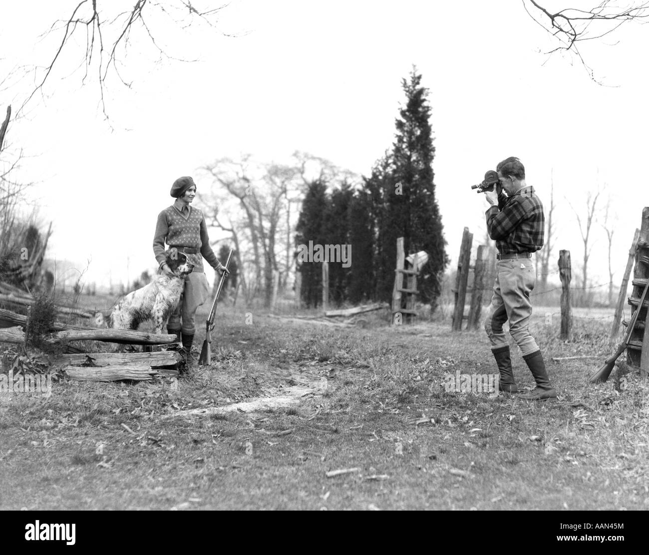 1930 COUPLE WEARING JODHPURS ET BOTTES D'ÉQUITATION FEMME EST posant avec un Setter anglais chien de fusil et l'homme est le tournage FILM AVEC Banque D'Images