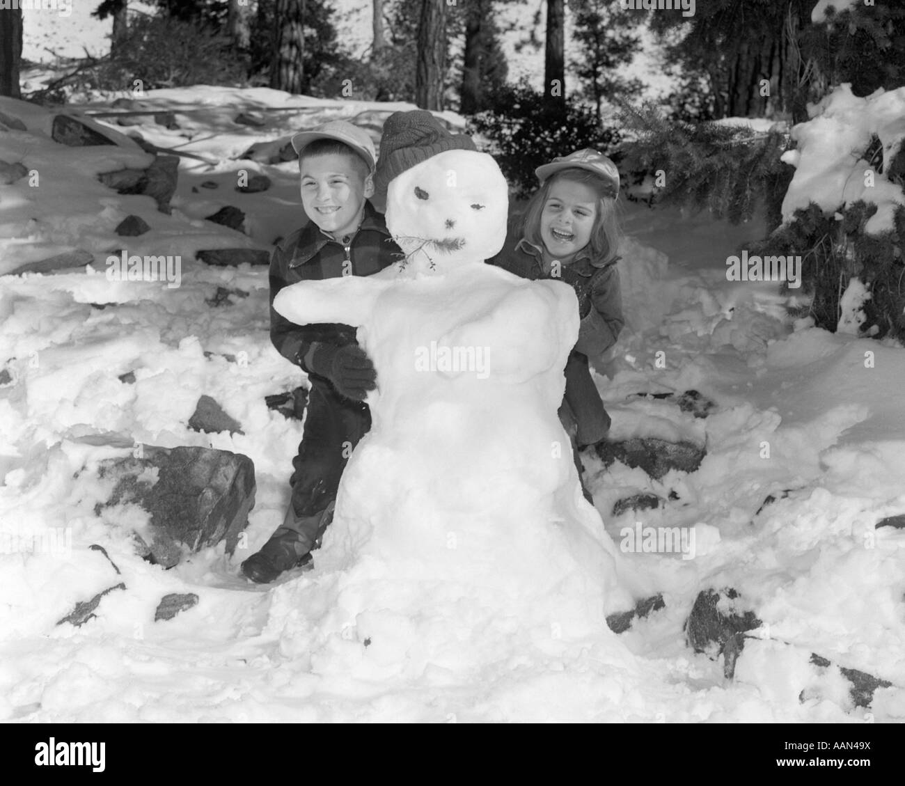 Années 1950 Années 1960 SMILING BOY AND GIRL UN BONHOMME ENSEMBLE DANS SNOWY WOODS Banque D'Images
