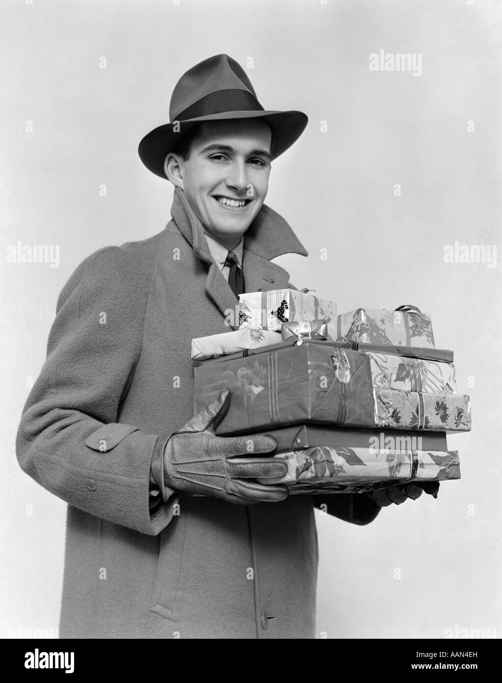 Années 1930 Années 1940 HOMME EN MANTEAU D'HIVER CHAPEAU ET DES GANTS  HOLDING PILE DE CADEAUX DE NOËL SMILING AT CAMERA Photo Stock - Alamy