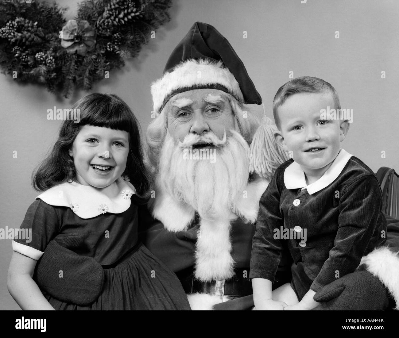 1950 PÈRE NOËL homme posant avec un jeune garçon et fille sur LAP SMILING PISCINE Banque D'Images