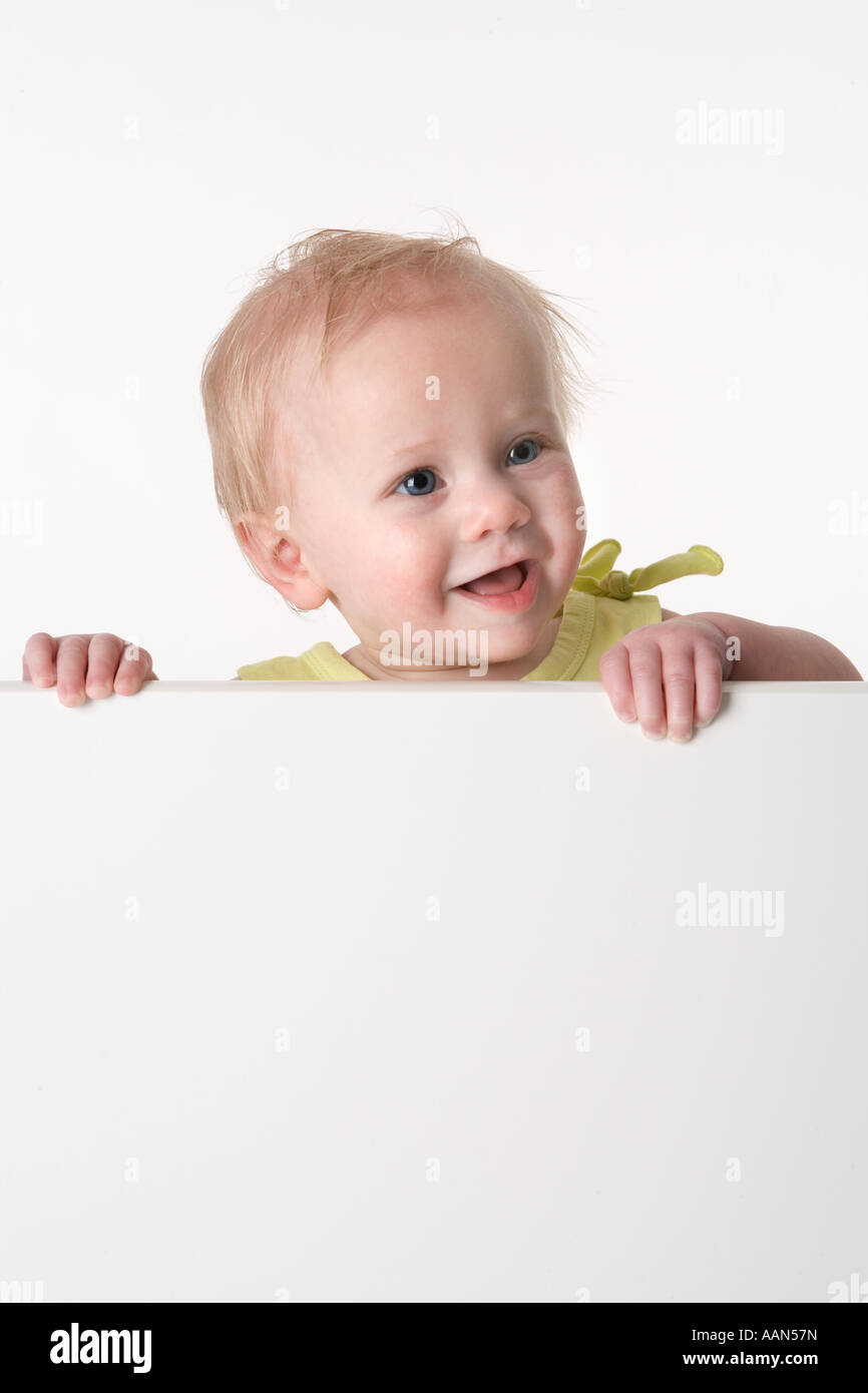 Bébé à la recherche sur une clôture avec une expression surprise Banque D'Images