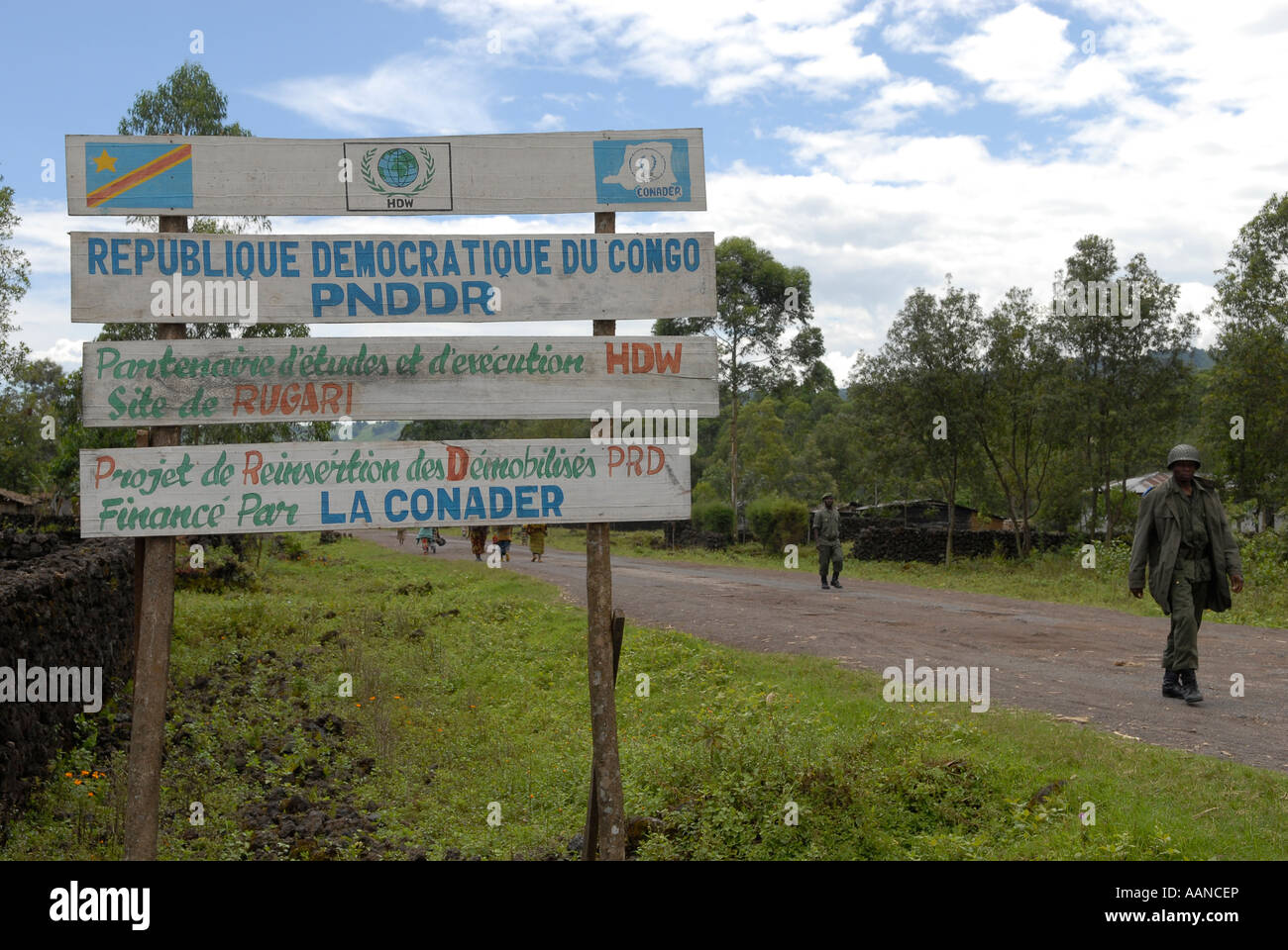 Les soldats du gouvernement congolais des FARDC marchent devant un panneau mentionnant le projet humanitaire PNDDR dans une zone rurale de la province du Nord-Kivu en RD Congo Afrique Banque D'Images