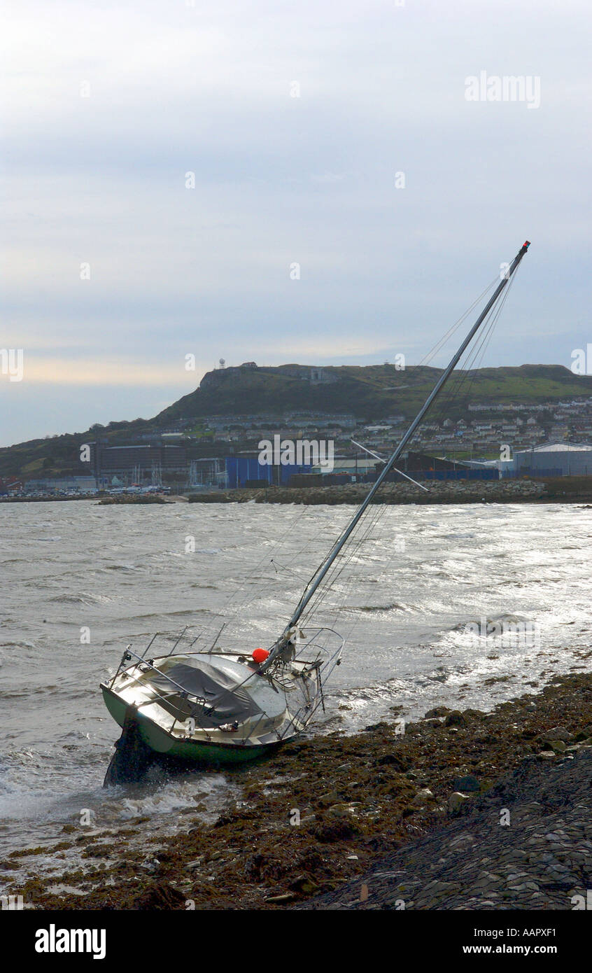 Un petit yacht de croisière s'est échoué au large de moorings après tempête au port de Portland, dans le Dorset England UK avec au-delà de Portland Banque D'Images