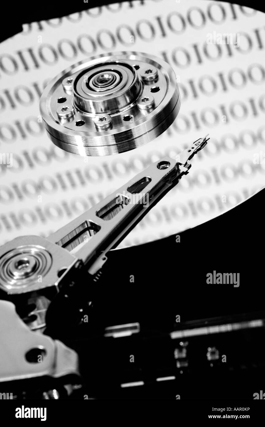 Disque dur d'un ordinateur exposé montrant le plateau de disque magnétique, la tête de lecture et d'écriture et le bras. Les nombres binaires représentant les données stockées sur le lecteur se reflètent sur le plateau de disque. Banque D'Images