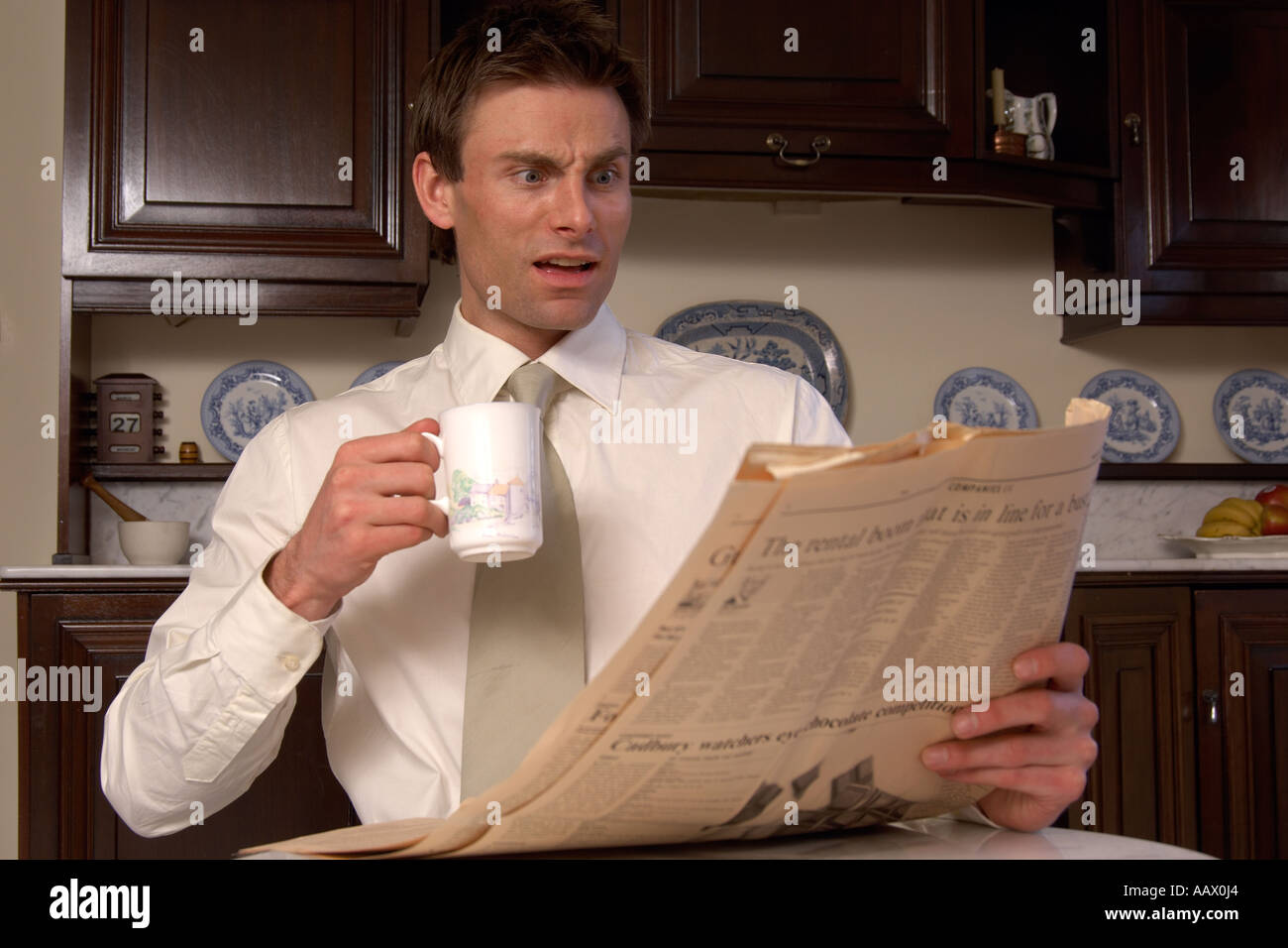 Homme lisant le journal tout en ayant une tasse de café surpris par son contenu Banque D'Images