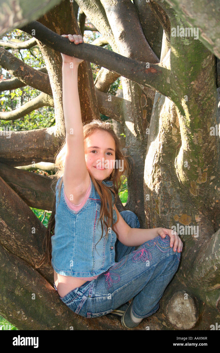 Jeune fille escalade un arbre habillé en denim Banque D'Images