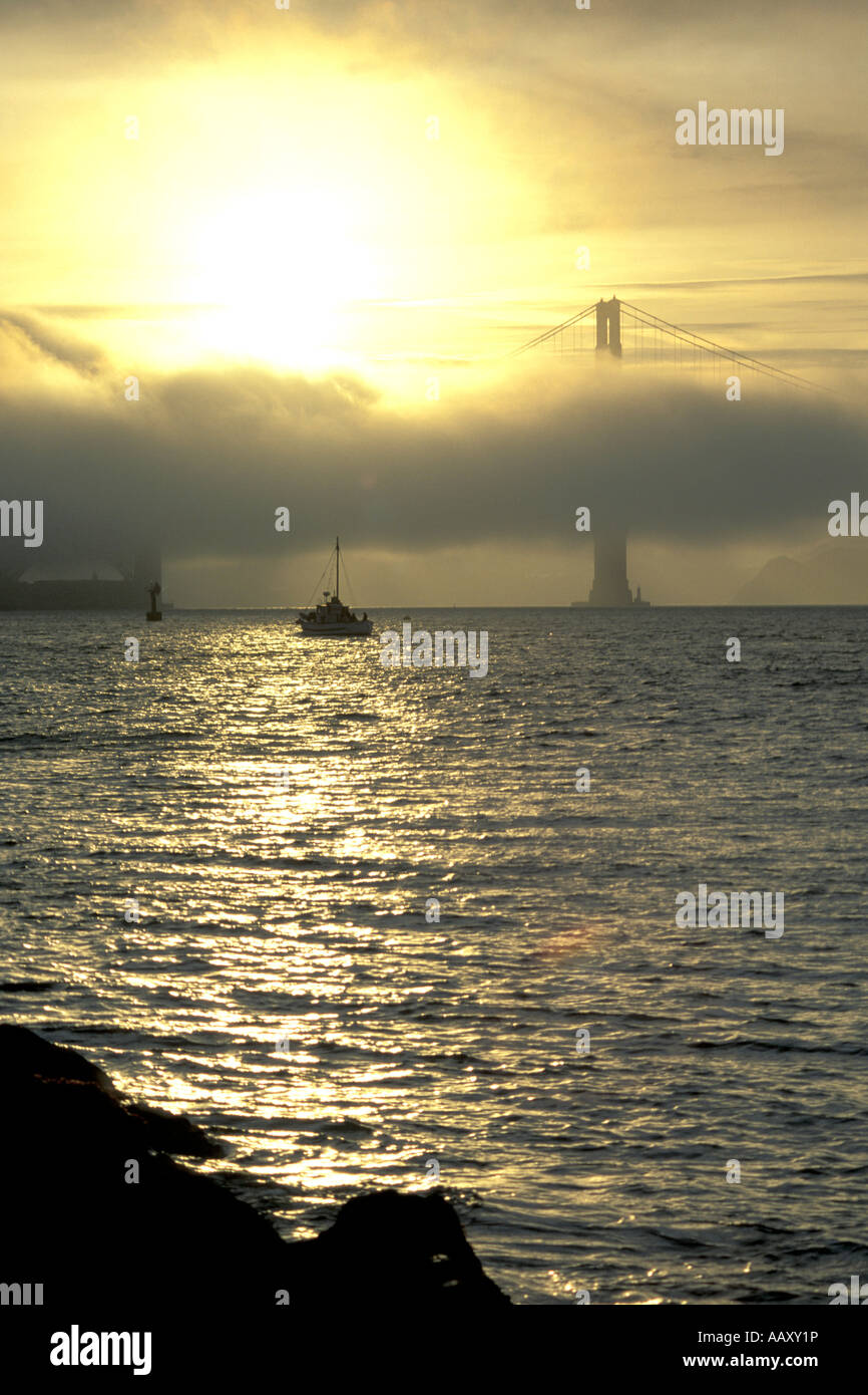 Bateau de pêche sous le Golden Gate Bridge San Francisco Bay avec du brouillard au coucher du soleil en Californie Banque D'Images