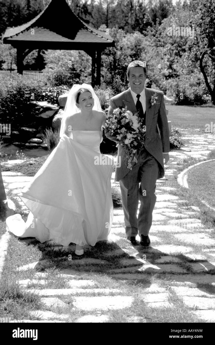 Noir et blanc photo de jeunes mariés lors de la cérémonie du mariage de marcher dans l'allée avec des sourires sur leurs visages et dans l'amour Banque D'Images