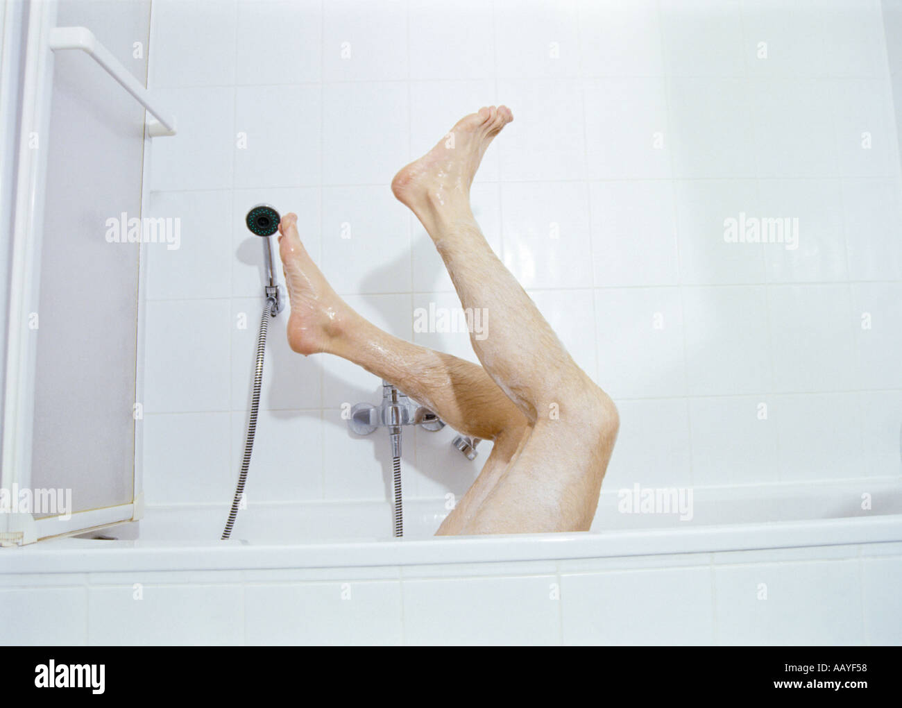 S'homme jambes poilues qui sort d'une baignoire Banque D'Images