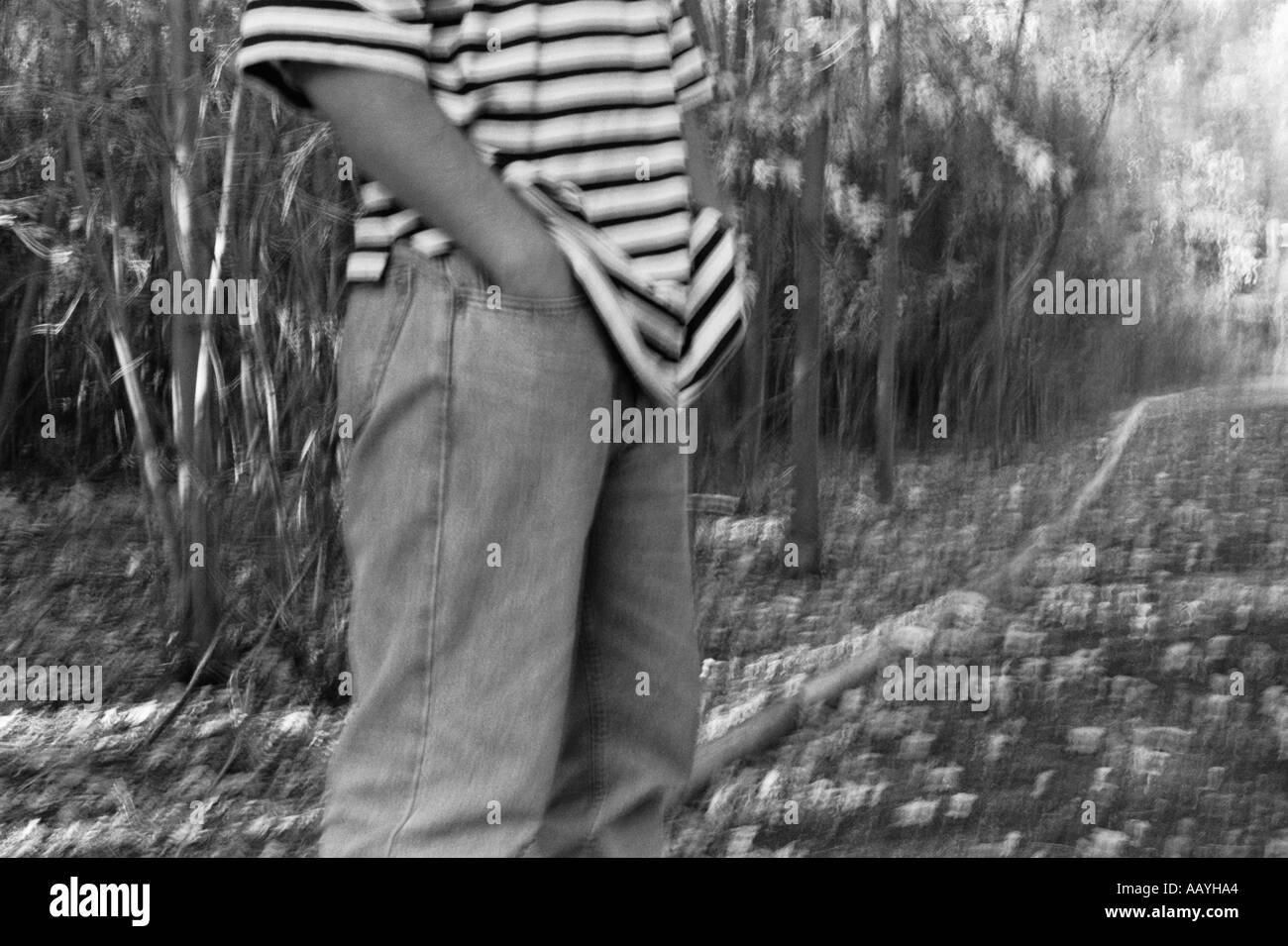 DPA70323 horizontale monochrome noir et blanc un homme portant des jeans et t-shirt à rayures met la main dans la poche Banque D'Images