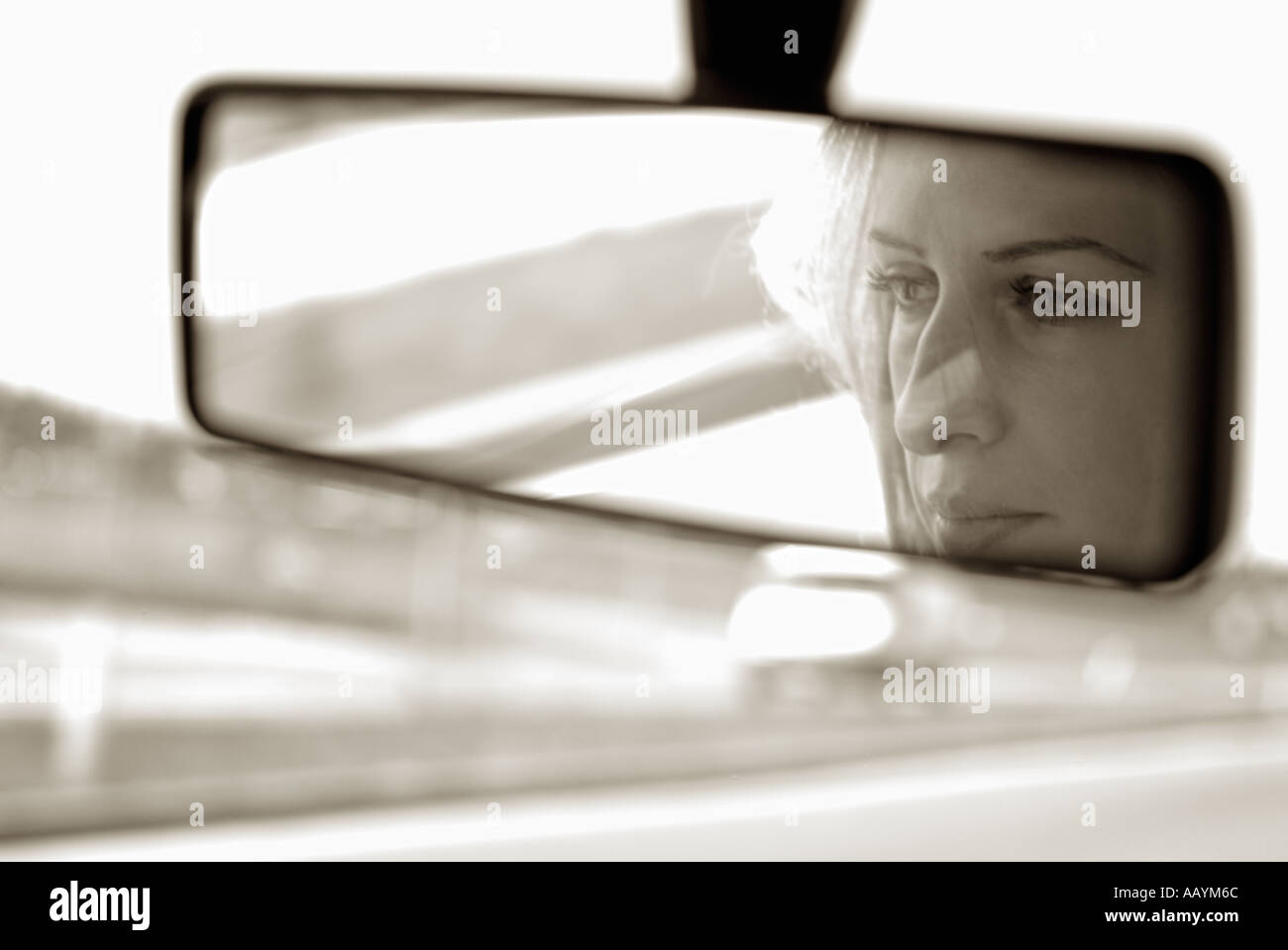 Femme au rétroviseur d'une voiture roulant sur une route Banque D'Images