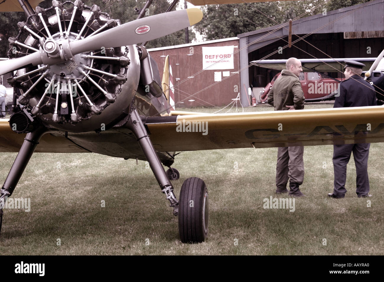 Chat pilote à l'ATC personne à côté de Boeing Stearman un biplan avec vieille voiture en arrière-plan à l'aérodrome Defford Juin 2005 Banque D'Images