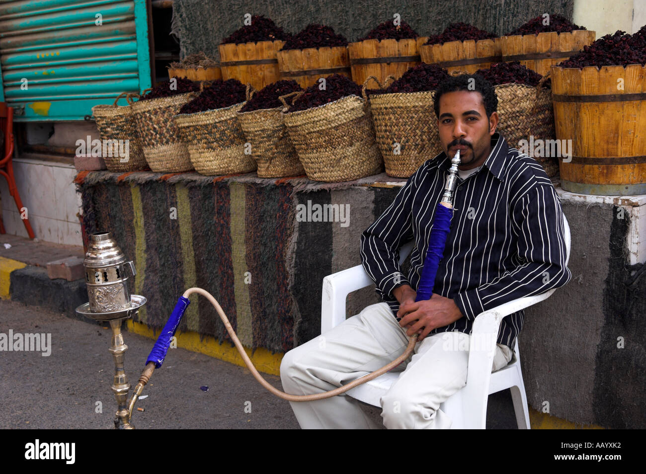 Portrait Men sitting relaxing fumer shisha pipe en face de barils de hibiscus tea Hurghada Banque D'Images