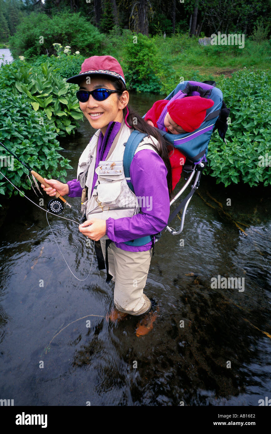 Portrait d'une femme japonaise de pêche à la mouche avec sa fille de 5 mois sur son dos dans la rivière de l'Oregon Metolius Banque D'Images