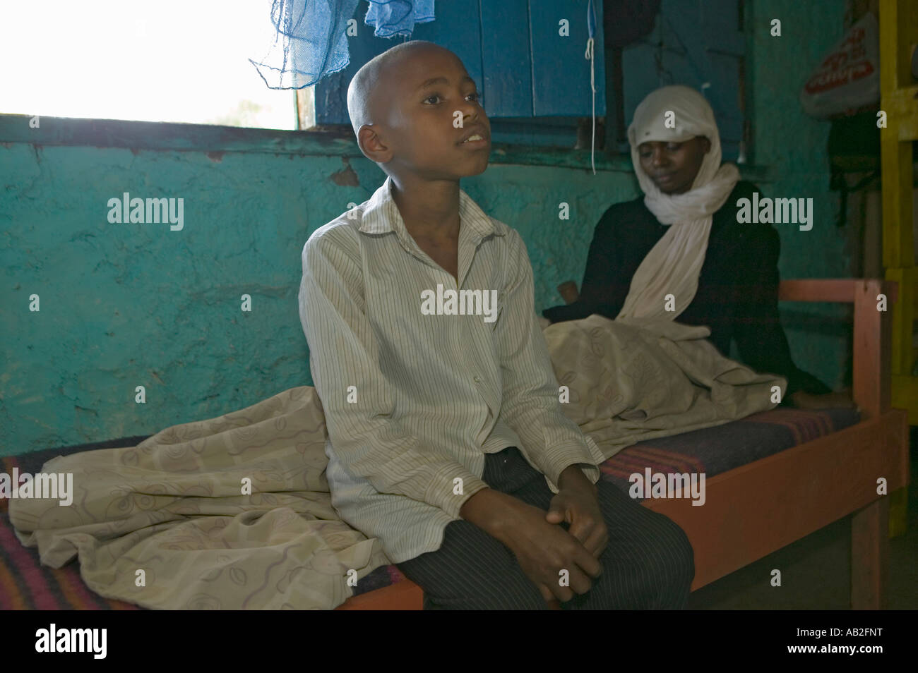 Un jeune garçon est assis au chevet de sa mère qui est infecté par le VIH SIDA à Pepo La Tumaini Jangwani VIH SIDA Community Reha Banque D'Images