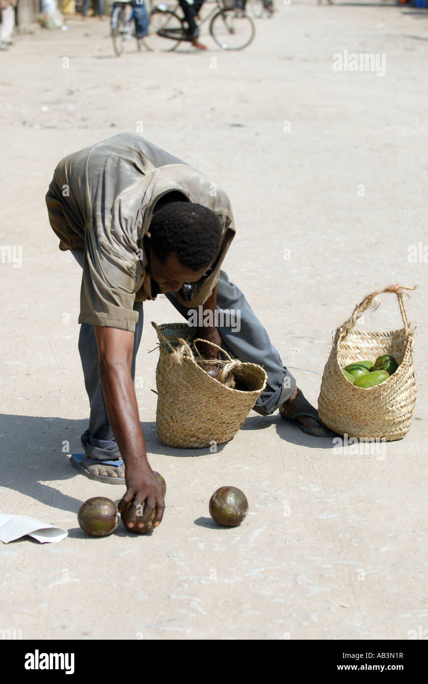 Un vendeur avocat prendra ses produire hors du sol après la poignée de son panier a éclaté dans la ville portuaire de Tanga, Tanzanie Banque D'Images