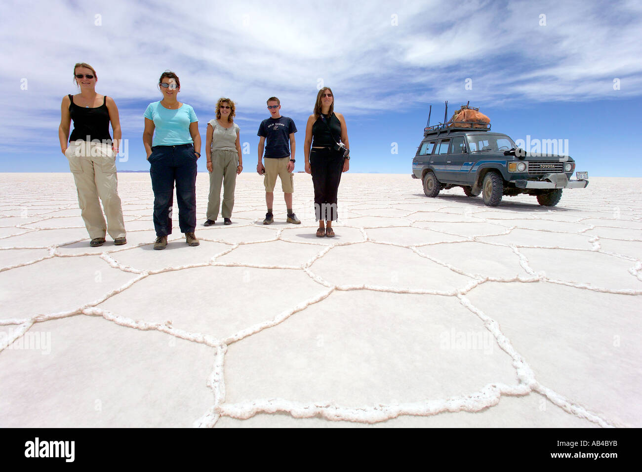 Un groupe de touristes posant sur le sel de Bolivie (Salar de Uyuni) au cours d'un safari en jeep. Banque D'Images