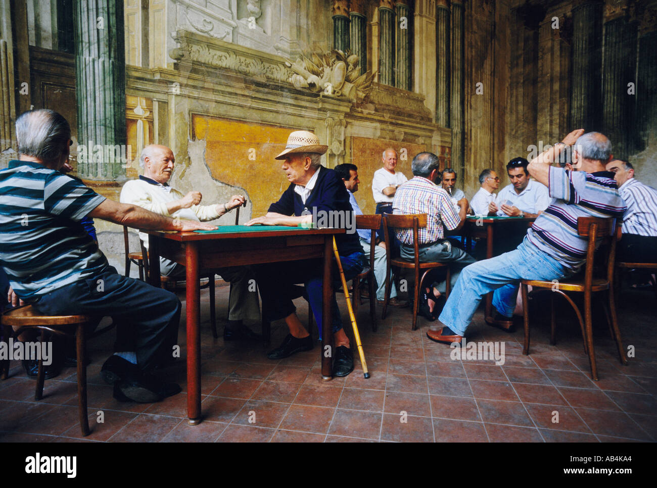 Sorrente. Italie. Un groupe d'hommes italiens se réunissent pour jouer à des cartes sur fond de fresques en fading dans la Sedil Dominova. Banque D'Images