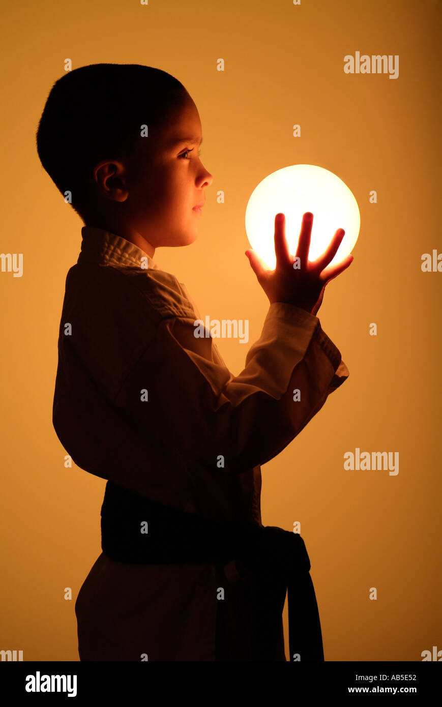 Young boy holding ball shinning Banque D'Images