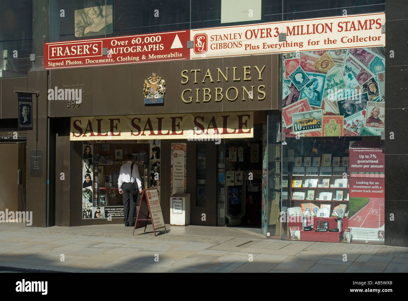 Le magasin de timbres Strand Stanley Gibbons avec un homme qui regarde l'exposition de la fenêtre avant du magasin et le Royal Adjur avec philatélie illustrations Londres Angleterre Royaume-Uni Banque D'Images