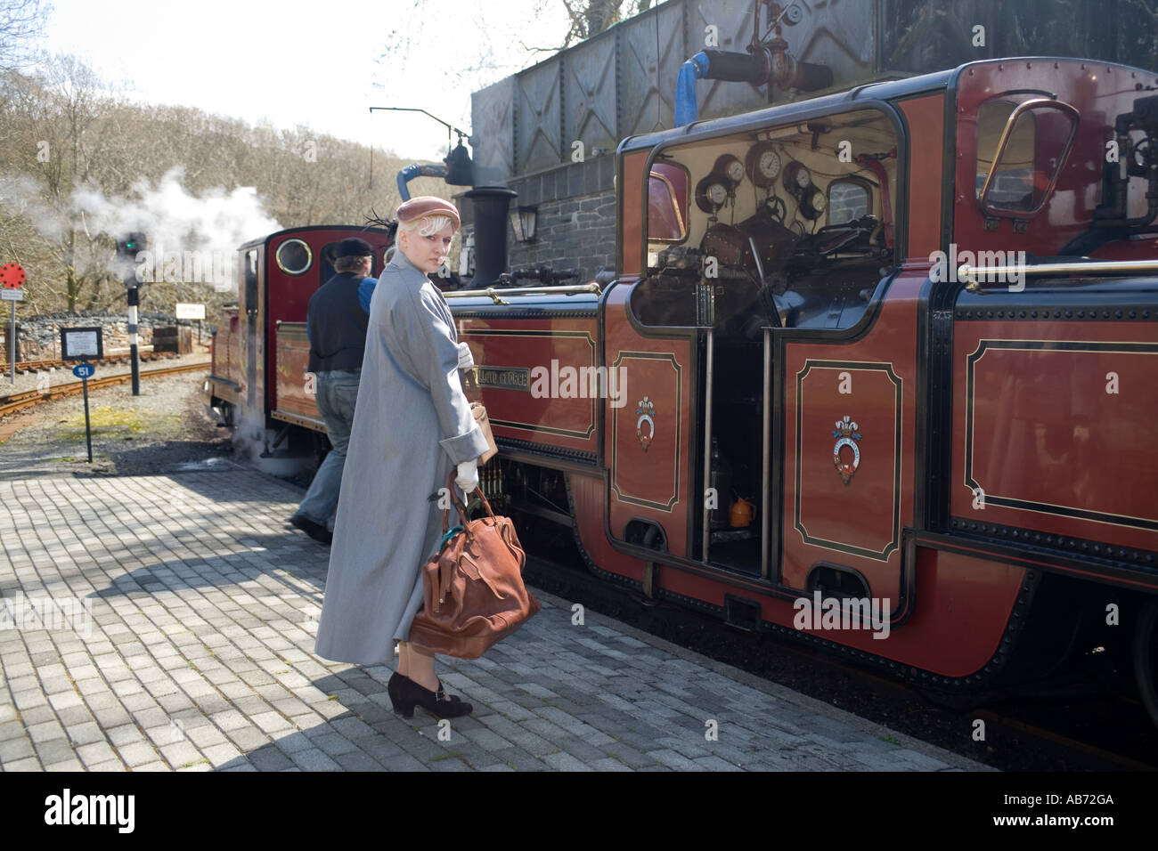 Jeune femme en vêtements de style années 1940, à Tan y Bwlch Ffestiniog Railway station, machine à vapeur, au nord du Pays de Galles, Royaume-Uni Banque D'Images