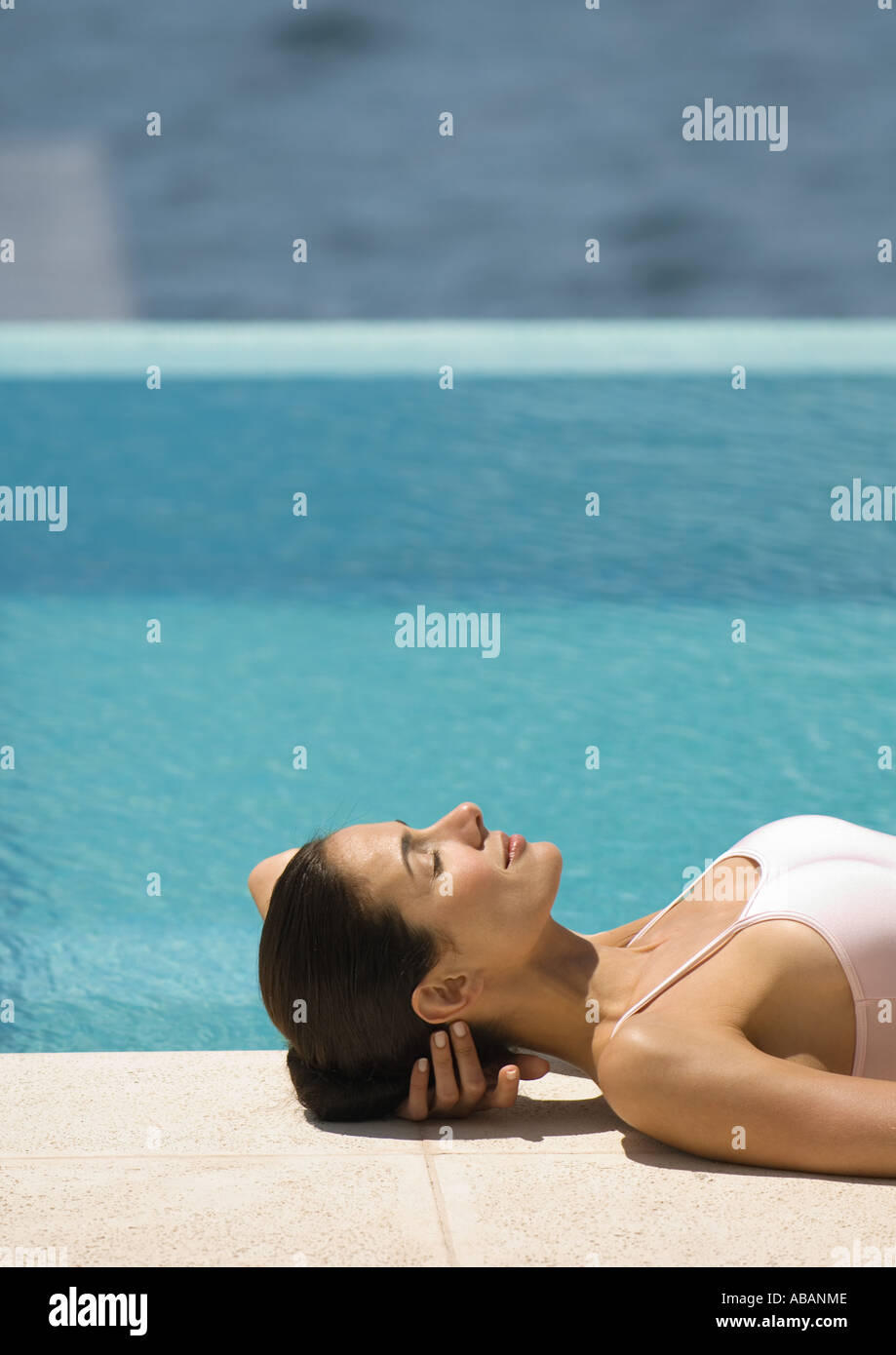 Femme étendue sur le sol près du bord de la piscine Banque D'Images