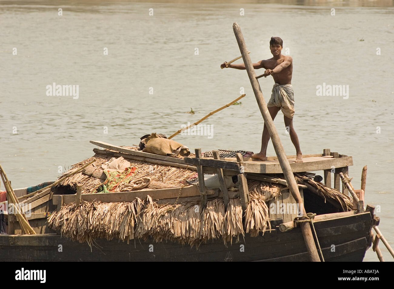 L'homme du Bangladesh l'aviron un gros cargo dans Raimangal River près de Khulna . Banque D'Images
