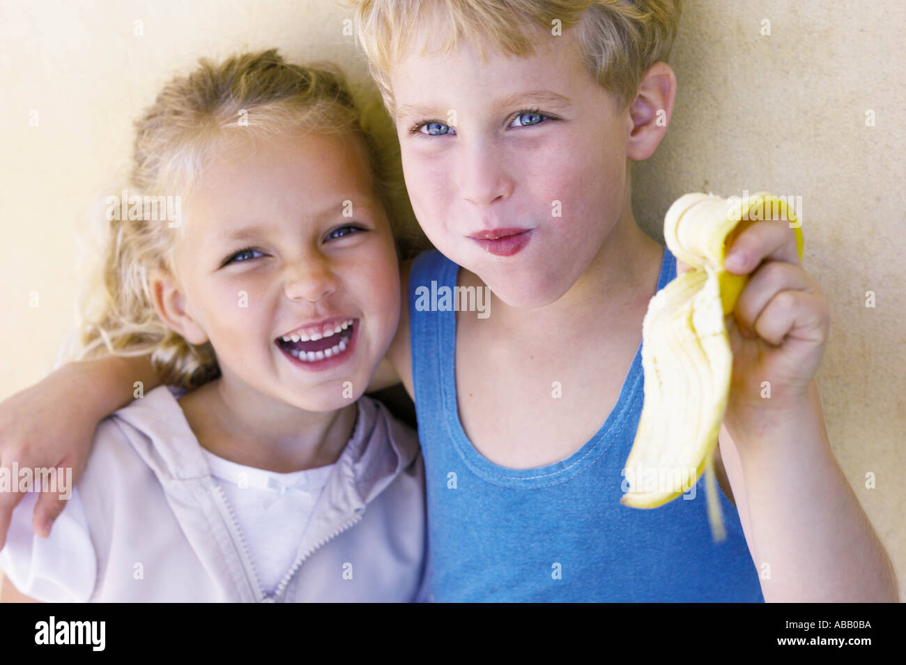 Boy hugging soeur et manger banana Banque D'Images