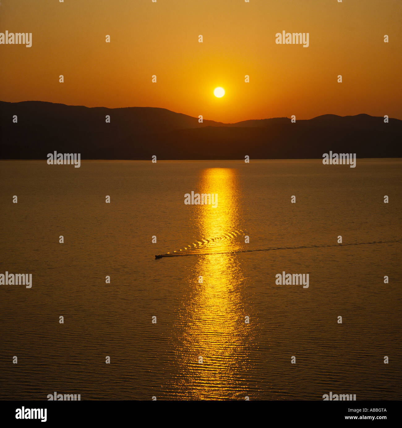Coucher du soleil sur la baie d'Argostoli avec ondulations et service de bateau en réflexions sur l'île de Céphalonie les îles Grecques Banque D'Images