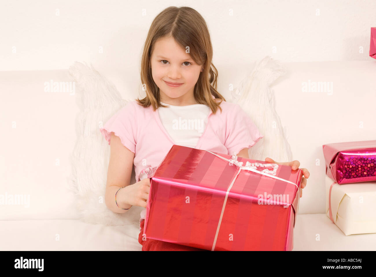 Portrait of Girl sitting on sofa holding presents Banque D'Images