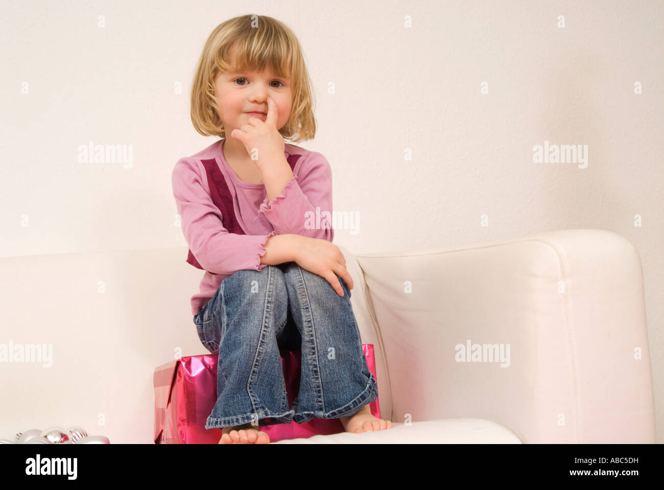 Portrait de petite fille assise sur présent sur canapé Banque D'Images