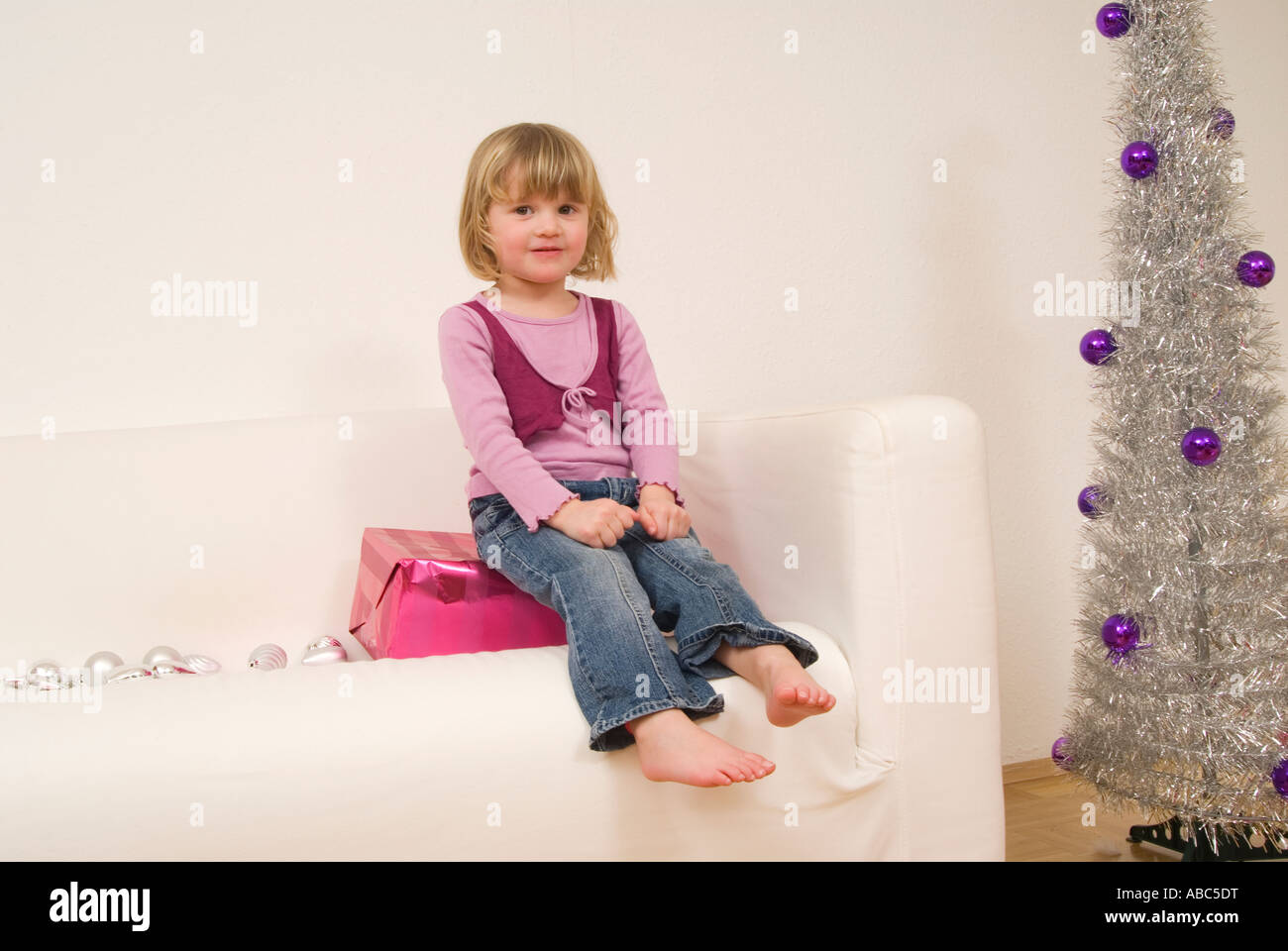 Portrait de petite fille assise sur le canapé près de l'arbre de Noël Banque D'Images