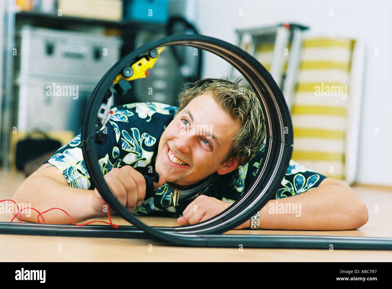 Jeune homme jouant avec petite voiture speedway Banque D'Images