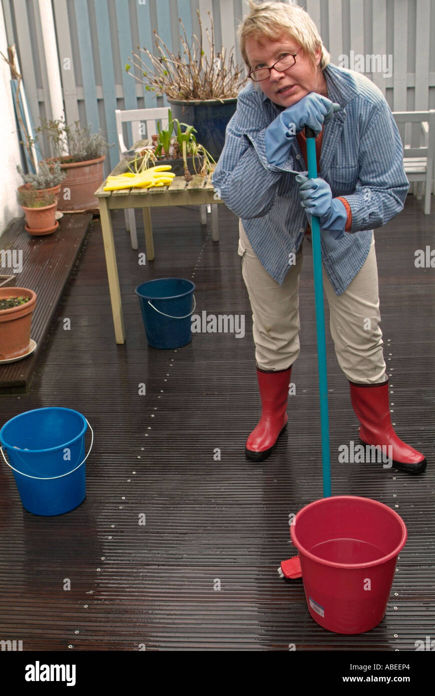 Monsieur femme à l'âge de 40 à 50 ans portant des rubberboots avec un mop  de lavage de plancher de bois e terrasse ayant une pause Photo Stock - Alamy
