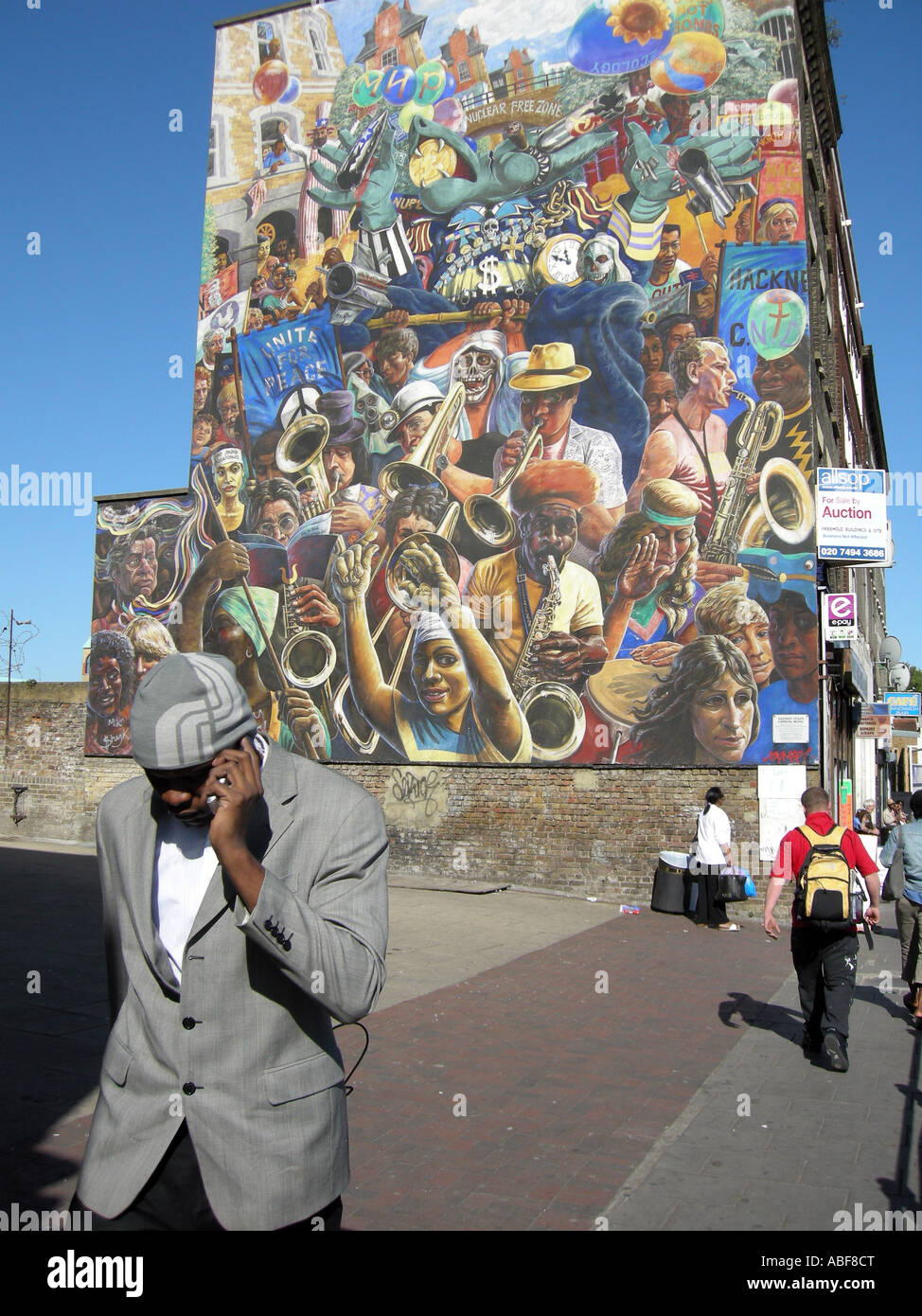 L'afro-caraïbes man walking passé une murale communautaire À HACKNEY London England Photo © Julio Etch Banque D'Images